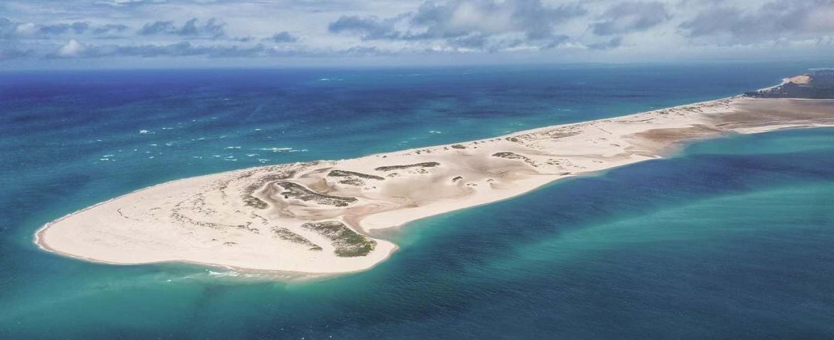 Aerial view of a white sand island surrounded by clear blue ocean waters