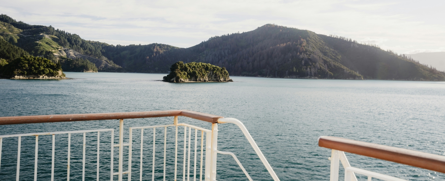 View from cruise ship deck overlooking islands and calm ocean waters